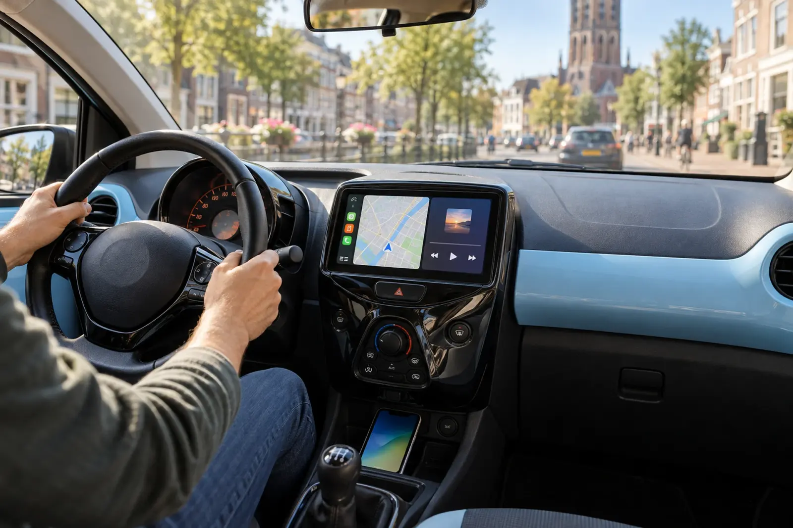 CarPlay bestellen in Leeuwarden: navigatie op een ingebouwd CarPlay-scherm in een compacte stadsauto met lichtblauw dashboard, geparkeerd aan een gracht in Leeuwarden